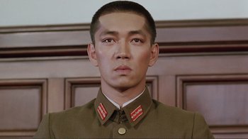 Movie still from “Merry Christmas Mr. Lawrence” (1983), directed by Nagisa Ôshima – A man wearing a uniform and a badge on his chest; Close Up shot, Low angle