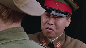 Movie still from “Merry Christmas Mr. Lawrence” (1983), directed by Nagisa Ôshima – A man in a red hat and a brown uniform; Close Up shot, Over the shoulder angle