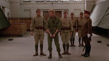 Movie still from “Merry Christmas Mr. Lawrence” (1983), directed by Nagisa Ôshima – A group of men standing next to each other in a room; Wide shot, Low angle