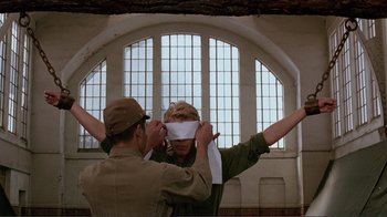 Movie still from “Merry Christmas Mr. Lawrence” (1983), directed by Nagisa Ôshima – A man and a woman are blindfolded in front of a window; Medium shot, Over the shoulder angle