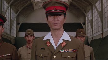 Movie still from “Merry Christmas Mr. Lawrence” (1983), directed by Nagisa Ôshima – A man in a military uniform standing in front of other men; Close Up shot, Low angle