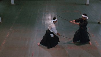 Movie still from “Merry Christmas Mr. Lawrence” (1983), directed by Nagisa Ôshima – Two people are practicing martial arts on a wooden floor; Wide shot, High angle