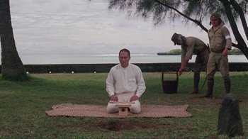 Movie still from “Merry Christmas Mr. Lawrence” (1983), directed by Nagisa Ôshima – A man kneeling on the ground in front of another man; Wide shot, High angle
