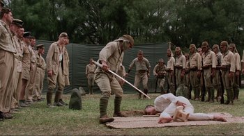Movie still from “Merry Christmas Mr. Lawrence” (1983), directed by Nagisa Ôshima – A group of men standing next to each other on a field; Wide shot, High angle