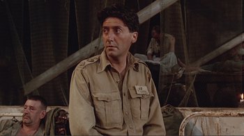 Movie still from “Merry Christmas Mr. Lawrence” (1983), directed by Nagisa Ôshima – A man in a military uniform sitting on a couch; Medium shot, Over the shoulder angle