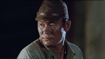 Movie still from “Merry Christmas Mr. Lawrence” (1983), directed by Nagisa Ôshima – A person wearing a hat and looking at the camera; Close Up shot, Low angle