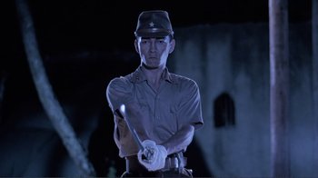 Movie still from “Merry Christmas Mr. Lawrence” (1983), directed by Nagisa Ôshima – A man holding a baseball bat while wearing a hat; Medium shot, Low angle
