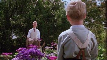 Movie still from “Merry Christmas Mr. Lawrence” (1983), directed by Nagisa Ôshima – A man and a boy are in a flower garden; Medium shot, Over the shoulder angle