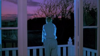 Movie still from “Merry Christmas Mr. Lawrence” (1983), directed by Nagisa Ôshima – A man standing on a porch looking out at the sunset; Wide shot, Low angle