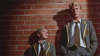 Movie still from “Merry Christmas Mr. Lawrence” (1983), directed by Nagisa Ôshima – Two young men in suits and ties are posing against a brick wall; Medium shot, Low angle