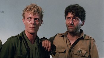 Movie still from “Merry Christmas Mr. Lawrence” (1983), directed by Nagisa Ôshima – A couple of men standing next to each other; Close Up shot, Over the shoulder angle