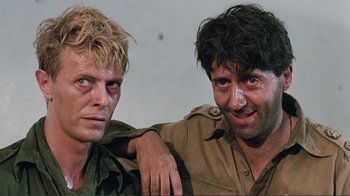 Movie still from “Merry Christmas Mr. Lawrence” (1983), directed by Nagisa Ôshima – A couple of men standing next to each other; Close Up shot, Low angle