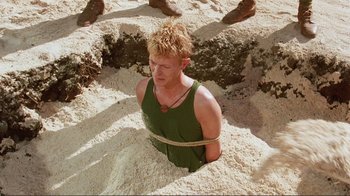 Movie still from “Merry Christmas Mr. Lawrence” (1983), directed by Nagisa Ôshima – A man tied to a rope in the middle of the sand; Medium shot, High angle