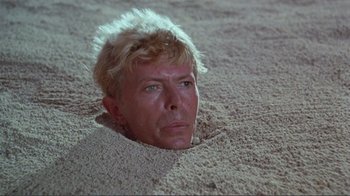 Movie still from “Merry Christmas Mr. Lawrence” (1983), directed by Nagisa Ôshima – A person laying in the sand; Close Up shot, High angle