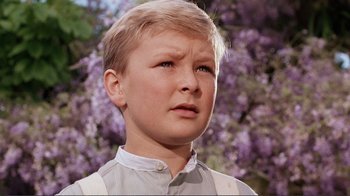 Movie still from “Merry Christmas Mr. Lawrence” (1983), directed by Nagisa Ôshima – A young boy in front of a tree with purple flowers; Close Up shot, Low angle