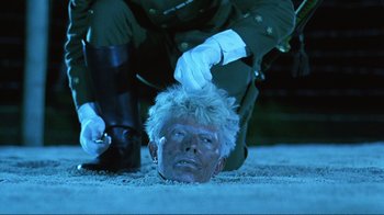 Movie still from “Merry Christmas Mr. Lawrence” (1983), directed by Nagisa Ôshima – A man in a green uniform laying on the ground with his head on the ground; Close Up shot, High angle