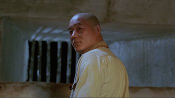 Movie still from “Merry Christmas Mr. Lawrence” (1983), directed by Nagisa Ôshima – A bald man in a white shirt is standing in a room; Close Up shot, Low angle