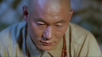 Movie still from “Merry Christmas Mr. Lawrence” (1983), directed by Nagisa Ôshima – A man with bald head wearing a long necklace; Close Up shot, High angle