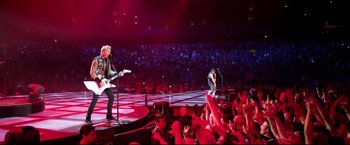 Movie still from “Metallica Through the Never” (2013), directed by Nimród Antal – A group of people on a stage at a concert; Extreme Wide shot, High angle