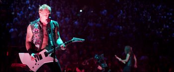 Movie still from “Metallica Through the Never” (2013), directed by Nimród Antal – A man playing a guitar in front of an audience; Wide shot, High angle