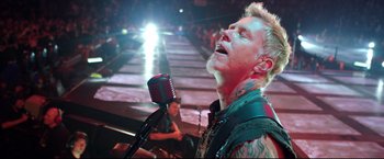Movie still from “Metallica Through the Never” (2013), directed by Nimród Antal – A man with a microphone in front of a crowd of onlookers; Close Up shot, Low angle
