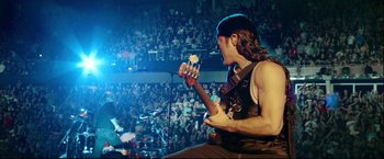 Movie still from “Metallica Through the Never” (2013), directed by Nimród Antal – A man holding a guitar in front of an audience; Medium shot, High angle