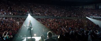 Movie still from “Metallica Through the Never” (2013), directed by Nimród Antal – A crowd of people watching a man on a stage; Extreme Wide shot, High angle