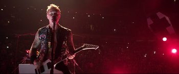 Movie still from “Metallica Through the Never” (2013), directed by Nimród Antal – A person with a guitar on a stage; Medium shot, High angle