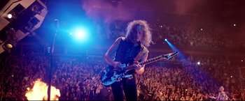 Movie still from “Metallica Through the Never” (2013), directed by Nimród Antal – A person with a guitar in front of an audience; Wide shot, High angle