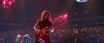 Movie still from “Metallica Through the Never” (2013), directed by Nimród Antal – A man playing a guitar in front of an audience; Medium shot, High angle