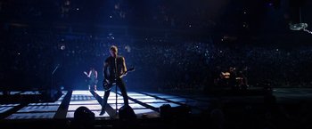 Movie still from “Metallica Through the Never” (2013), directed by Nimród Antal – A man with a guitar on a stage in front of an audience; Wide shot, High angle