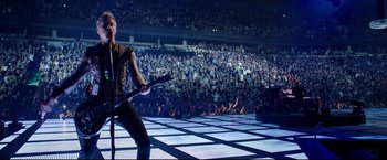 Movie still from “Metallica Through the Never” (2013), directed by Nimród Antal – A man with a guitar in front of an audience; Wide shot, High angle