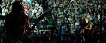 Movie still from “Metallica Through the Never” (2013), directed by Nimród Antal – A person playing a guitar in front of an audience; Wide shot, High angle