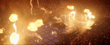 Movie still from “Metallica Through the Never” (2013), directed by Nimród Antal – A crowd of people watching a person on a motorcycle on a stage; Extreme Wide shot, High angle