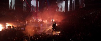 Movie still from “Metallica Through the Never” (2013), directed by Nimród Antal – A crowd of people are watching a band perform on a stage; Extreme Wide shot, High angle