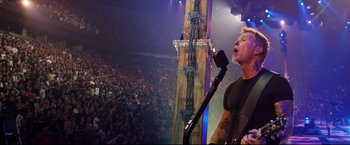 Movie still from “Metallica Through the Never” (2013), directed by Nimród Antal – A man with a microphone in front of an audience; Medium shot, Low angle