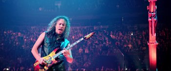 Movie still from “Metallica Through the Never” (2013), directed by Nimród Antal – A man playing a guitar in front of an audience; Medium shot, High angle