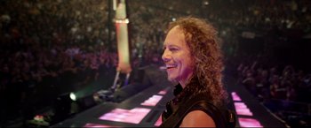 Movie still from “Metallica Through the Never” (2013), directed by Nimród Antal – A man with curly red hair is smiling at a concert; Close Up shot, High angle