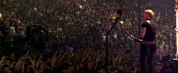 Movie still from “Metallica Through the Never” (2013), directed by Nimród Antal – A crowd of people in a large room with their hands up; Extreme Wide shot, High angle