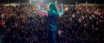 Movie still from “Metallica Through the Never” (2013), directed by Nimród Antal – A person with a guitar in front of an audience; Wide shot, High angle