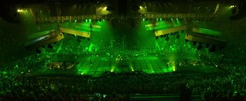 Movie still from “Metallica Through the Never” (2013), directed by Nimród Antal – A large stage with green lights and people in the background; Extreme Wide shot, Overhead angle