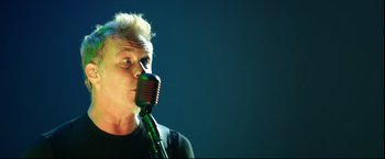 Movie still from “Metallica Through the Never” (2013), directed by Nimród Antal – A man with blonde hair is singing into a microphone; Close Up shot, Low angle