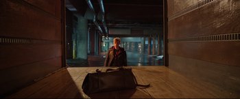 Movie still from “Metallica Through the Never” (2013), directed by Nimród Antal – A man standing in front of a bag on the floor; Wide shot, High angle