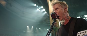 Movie still from “Metallica Through the Never” (2013), directed by Nimród Antal – A man with a beard is singing into a microphone; Close Up shot, Low angle