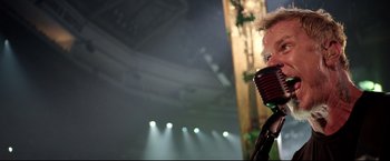 Movie still from “Metallica Through the Never” (2013), directed by Nimród Antal – A person with a microphone on a stage; Close Up shot, Low angle