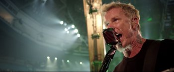 Movie still from “Metallica Through the Never” (2013), directed by Nimród Antal – A man holding a microphone up to his mouth; Close Up shot, Low angle