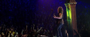 Movie still from “Metallica Through the Never” (2013), directed by Nimród Antal – A person playing a guitar in front of an audience; Wide shot, High angle