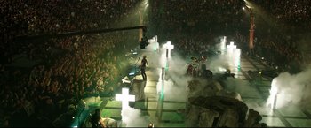 Movie still from “Metallica Through the Never” (2013), directed by Nimród Antal – A crowd of people watching a band perform on a stage; Extreme Wide shot, High angle
