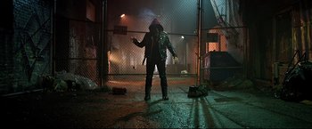 Movie still from “Metallica Through the Never” (2013), directed by Nimród Antal – A man in a leather jacket standing in front of a chain link fence; Wide shot, Low angle