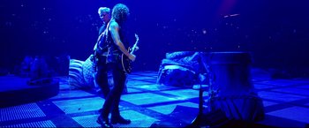 Movie still from “Metallica Through the Never” (2013), directed by Nimród Antal – A couple of people that are on a stage; Wide shot, Low angle